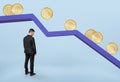 Businessman standing under falling graph with golden coins rolling down Royalty Free Stock Photo