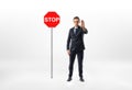 Businessman standing on white background making stop hand gesture with traffic sign beside him. Royalty Free Stock Photo