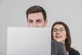 Businessman standing, working with laptop. Inquisitive woman is looking over his shoulder at the screen, her curious Royalty Free Stock Photo