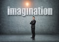 Businessman stands with big 3d 'imagination' word above