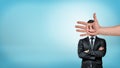 A businessman stands in a front view with folded arms behind a giant male hand with a smiley face covering his head. Royalty Free Stock Photo