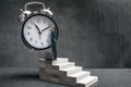 Businessman stands on stairs and tries to change clock hand