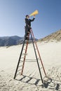 Businessman On Stepladder Using Megaphone In Desert