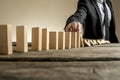 Businessman stopping domino effect with his finger Royalty Free Stock Photo