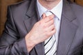 Businessman straightens his tie. Gentleman wearing black suit, shirt and tie, tuxedo