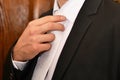 Businessman straightens his white tie