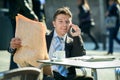 Businessman on street bar having breakfast coffee reading newspaper news talking on mobile phone Royalty Free Stock Photo