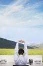 Businessman Stretching At Office Desk On Field