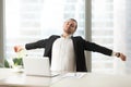 Businessman stretching out at desk with laptop