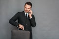 Businessman studio standing isolated on grey with laptop case checking time on watch talking on smartphone concerned Royalty Free Stock Photo