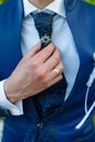 Businessman in a stylish blue suit with patterns straightens tie. Stylish man in an expensive suit and tie and jacket, close-up. Royalty Free Stock Photo