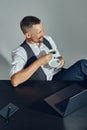 Businessman with stylish mustache, dressed in classic suit is smiling, looking away while sitting at table in office and Royalty Free Stock Photo