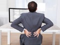 Businessman suffering from backache while sitting at desk Royalty Free Stock Photo