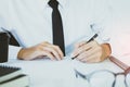 Businessman in a suit and black tie using a pen writing on paper for the document.Sign signature legally binding law