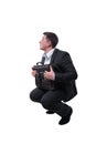 Businessman in a suit with a briefcase in his hands crouched down isolated on white background.