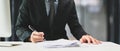 A businessman in suit hand holding pen filling paper business document or signing contract at office desk. Royalty Free Stock Photo