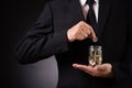 Businessman in suit is hand putting coin into jar. Finance Savings, investment, success and profitable business concept Royalty Free Stock Photo