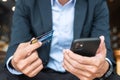 Businessman in suit holding credit card and using touchscreen smartphone for online shopping while making orders in the cafe or Royalty Free Stock Photo