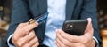 Businessman in suit holding credit card and using touchscreen smartphone for online shopping while making orders in the cafe or Royalty Free Stock Photo