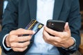 Businessman in suit holding credit card and using touchscreen smartphone for online shopping while making orders in the cafe or Royalty Free Stock Photo