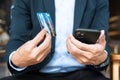 Businessman in suit holding credit card and using touchscreen smartphone for online shopping while making orders in the cafe or Royalty Free Stock Photo