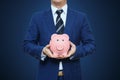 Businessman in suit is holding piggy bank. Businessman holding pig money box. Finance Savings concept