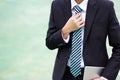 Businessman in a suit holding a tablet and adjusting a necktie. Royalty Free Stock Photo