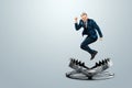 A businessman in a suit jumps into a large metal bear trap. Concept of problem solving, failure, crisis, mixed media Royalty Free Stock Photo