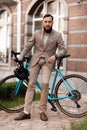 A businessman in a suit poses for a photo with bicycle. The image of a successful man. Promoting concern for the environment