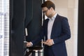 Businessman in suit pours coffee uses vending machine in office