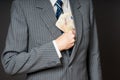 Businessman in suit putting banknotes in his jacket breast pocket. Business man is holding cash, stack of fifty euros money. Pers Royalty Free Stock Photo