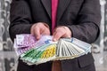 Businessman in suit showing and offering euro and dollar notes