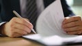 Businessman in suit signing and officially certificating important document closeup