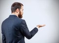 Businessman in suit standing and shows outstretched hand with open palm.