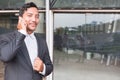 businessman in suit talking on smart phone while standing outside building. young asian male using cellphone for work at modern o Royalty Free Stock Photo