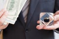 Businessman in suit, tie holds in hands drop of black oil of Brent brand in crystal cube.Pack of hundred dollars bills.Crisis in