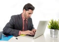 Businessman in suit and tie sitting at office desk working on computer laptop looking concentrated and pensive