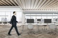 Businessman in suit walking in wooden conference room interior with city view, daylight, furniture and equipment. Design and ceo