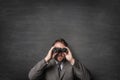 Businessman in a suit watching with binoculars