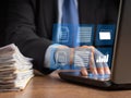 Businessman in a suit working at a laptop and digital documents with checkbox lists on virtual screen Royalty Free Stock Photo