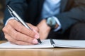 Businessman in suit writing something on notebook in office or cafe, hand of man holding pen with signature on paper report. Royalty Free Stock Photo