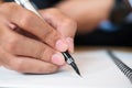 Businessman in suit writing something on notebook in office or cafe, hand of man holding pen with signature on paper report. Royalty Free Stock Photo