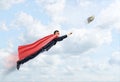 A businessman in a superhero cape flying in the sky trying to catch a 100 USD banknote.