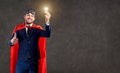 A businessman in a superhero costume with a glowing light bulb in his hand