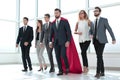Businessman in Superman cloak and business team standing in office lobby