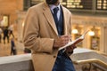 Businessman taking note using pen and notepad wearing cashmere jacket and business suit