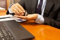 Businessman taking painkiller pill with laptop on wooden table.