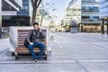 A businessman is talking on the cell phone while sitting on a bench in the street Royalty Free Stock Photo