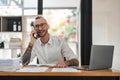 businessman talking on cell phone while working on computer in office Royalty Free Stock Photo