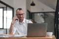 businessman talking on cell phone while working on computer in office Royalty Free Stock Photo